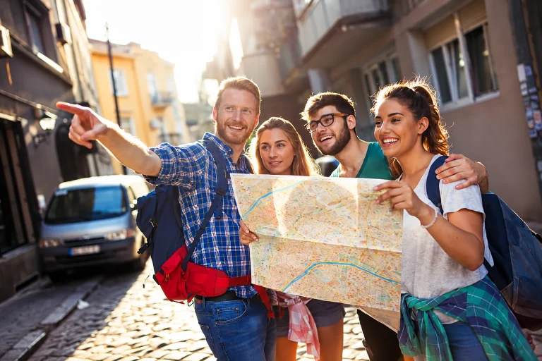 Grupo de cuatro viajeros consultando un mapa durante un paseo por la ciudad